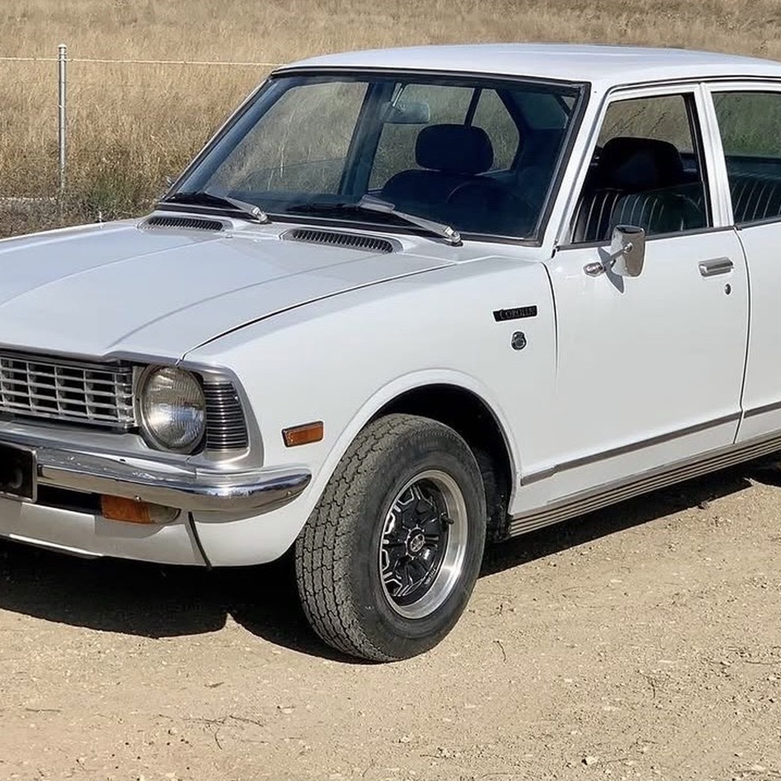 Toyota Corolla 1973 branco em estrada de terra, clássico para casamentos A&M Wedding Cars